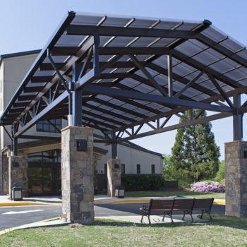 Standing Seam Skin System Canopy, 25’5” x 42’6”, 2.5/12 pitch. Glazing: 20mm Bronze Cellular Polycarbonate mounted to steel purlins, structure by others. Includes gutters and downspouts. Finish: Dark Bronze Anodized.